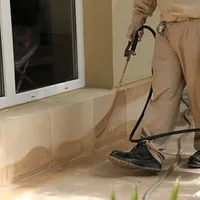 General pest control technician spraying exterior perimeter around a home in Ann Arbor, MI