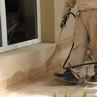 General pest control technician spraying exterior perimeter around a home in Ann Arbor, MI
